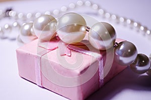 Luxurious pearl jewelry on a pink box. Snow-white pearls. Bijouterie. Jewelry. Snow-white beads on a white background. Brilliant p