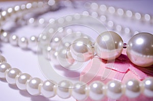 Luxurious pearl jewelry on a pink box. Snow-white pearls. Bijouterie. Jewelry. Snow-white beads on a white background. Brilliant p