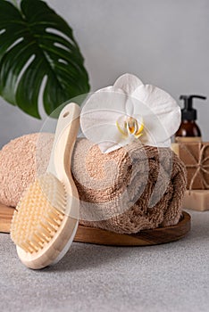 Luxurious spa setting with a rolled towel, white orchid, back brush and skincare products photo