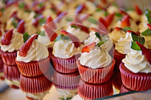 Luxurious wedding cupcakes in red and white color and with strawberry at the top
