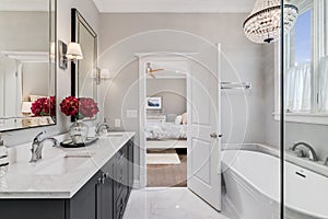 A luxurious white bathroom, looking towards bedroom.