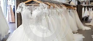 Luxurious white bridal gowns elegantly displayed on hangers in a high end boutique salon