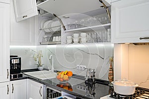 Luxurious white modern kitchen interior, drawers pulled out, doors open