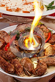 Luxuriously decorated table with roast meat and fire in the middle of the plate