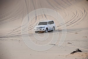 Luxurous white SUW 4x4 on desert safari on dunes exreme racing in arabia travel rally on sand in sports vehicle all