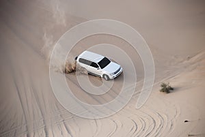 Luxurous white SUW 4x4 drifts on desert safari on dunes exreme racing in arabia travel rally on sand in sports vehicle photo