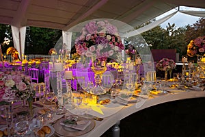 A luxury alfresco wedding reception set up at the countryside; white rustic tiffany chairs, top table flower arrangements