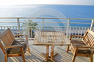 Luxury apartment condominium hotel balcony with wooden table, chairs facing Mediterranean sea, Promenade des Anglais, Nice, France