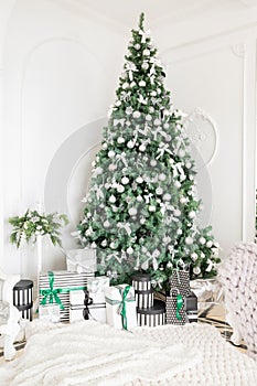 Luxury apartment decorated for christmas. Xmas tree with presents underneath in living room