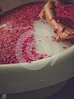 Luxury bath tub in spa with Asian woman`s bare legs showing through.