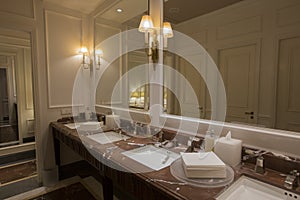 Luxury bathroom with brown beige granite marble stone counter vanity top board, two white ceramic sinks, large rectangular mirrors