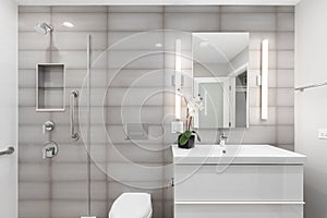 A luxury bathroom with a grey tiled wall and a white floating cabinet.