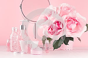 Luxury bathroom interior in romantic style - soft pink roses, cosmetic products for skin, body care, accessories, round mirror.