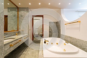 Luxury bathroom with large hydromassage, green marble and gold sinks