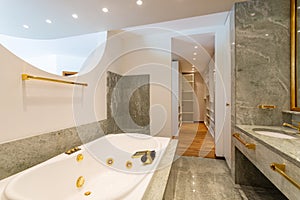 Luxury bathroom with large hydromassage, green marble and gold sinks