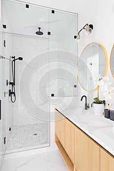 A luxury bathroom with a wood cabinet and marble walk-in shower.