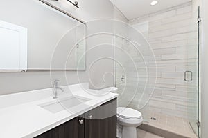 A modern bathroom with a wood cabinet and tiled shower.