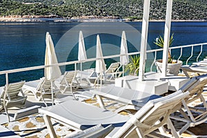 Luxury beach in a beautiful bay with white deck chairs. Magnificent views of the sea and mountains on a sunny day