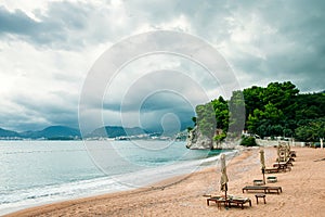 Luxury beach resort with sunbeds and umbrellas with rainy sky