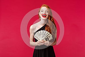 Luxury, beauty and money concept. Girl got expensive taste. Happy rich good-looking redhead woman in stylish black dress