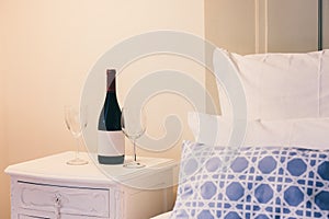 Luxury bedroom with bottle of red wine and glasses.