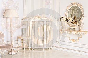 Luxury bedroom in light colors with mirror and folding screen. Elegant classic interior