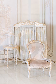 Luxury bedroom in light colors with mirror and folding screen. Elegant classic interior