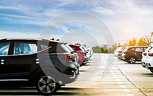 Luxury black, white and red new suv car parked on concrete parking area at factory with blue sky and clouds. Car stock for sale.