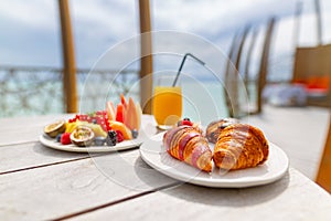 Luxury breakfast food on wooden table. Tropical resort morning sunlight with blurred water restaurant outdoors