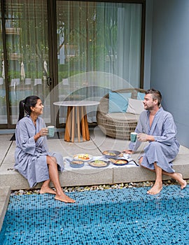 Luxury breakfast by a swimming pool during vacation, couple men and women having breakfast by pool