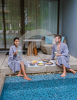 Luxury breakfast by a swimming pool during vacation, couple men and women having breakfast by pool