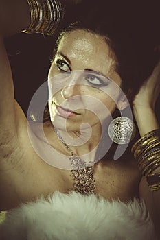 Luxury, brunette woman wearing white fur and gold jewelry
