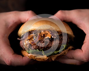 Luxury burger with a brioche bun on black background Hands grabbing burger