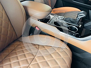 Luxury car brown leather interior. Part of brown leather car seat details with stitching isolated on black. Interior of prestige