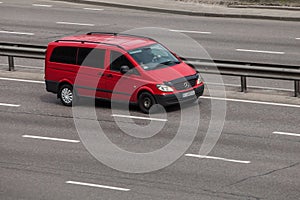 Luxury car red Mercedes Benz Viano speeding on empty highway