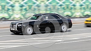 luxury car Rolls-Royce Ghost driving down the road at high speed
