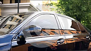Luxury car with tinted glass standing at parking, reflection of businessman photo