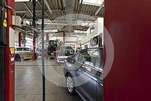 Luxury cars being repaired in a modern garage. View through red