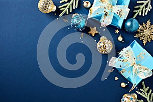 Luxury Christmas decorations, glistering gift boxes, fir branches, baubles, golden stars on dark blue background. Flat lay, top