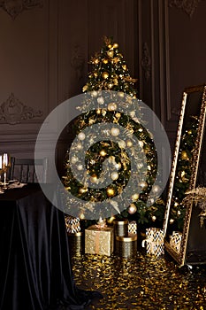 Luxury Christmas tree with gold gift boxes in dark interior