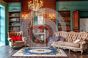 Luxury classic interior of home library. Sitting room with bookshelf, books, arm chair, sofa and fireplace