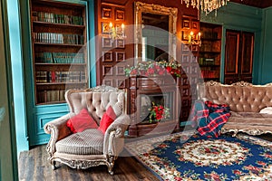 Luxury classic interior of home library. Sitting room with bookshelf, books, arm chair, sofa and fireplace