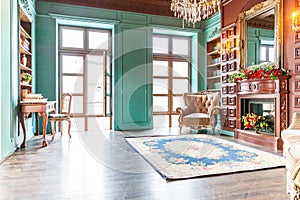 Luxury classic interior of home library. Sitting room with bookshelf, books, arm chair, sofa and fireplace