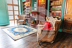 Luxury classic interior of home library. Sitting room with bookshelf, books, arm chair, sofa and fireplace