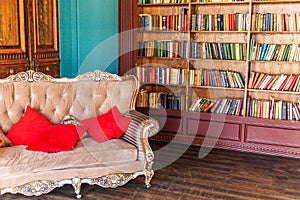 Luxury classic interior of home library. Sitting room with bookshelf, books, arm chair, sofa and fireplace