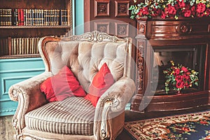 Luxury classic interior of home library. Sitting room with bookshelf, books, arm chair, sofa and fireplace