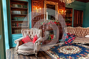 Luxury classic interior of home library. Sitting room with bookshelf, books, arm chair, sofa and fireplace. Clean and modern