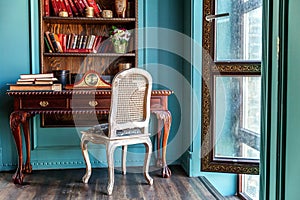 Luxury classic interior of home library. Sitting room with bookshelf, books, table and chair