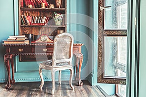 Luxury classic interior of home library. Sitting room with bookshelf, books, table and chair