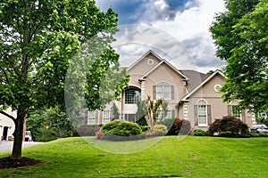 Luxury country home with large green lawn and landscaping in front yard